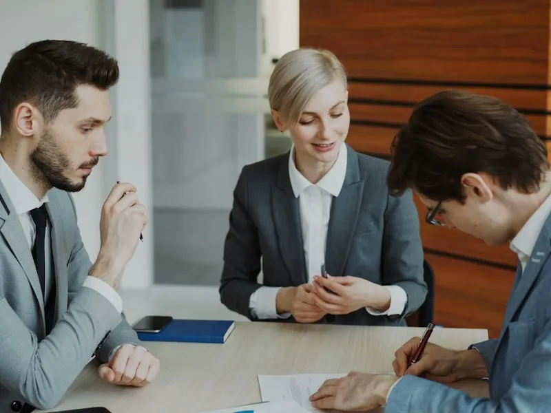 Business professionals signing a contract at a table