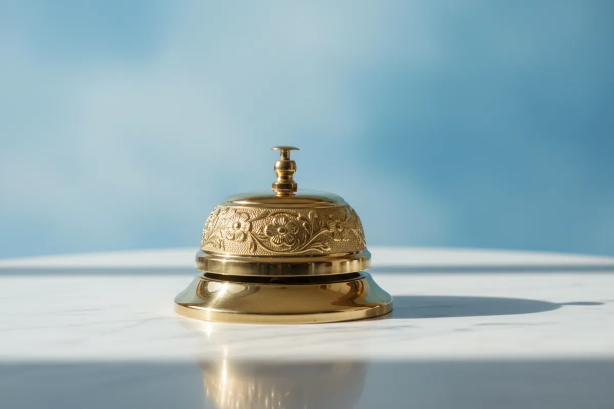 A gold-accented notification bell on a white marble surface with a blue gradient background