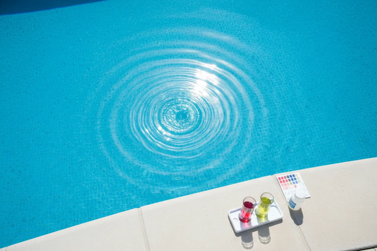Pristine pool surface with subtle ripples and a chemical tester kit on the deck nearby.