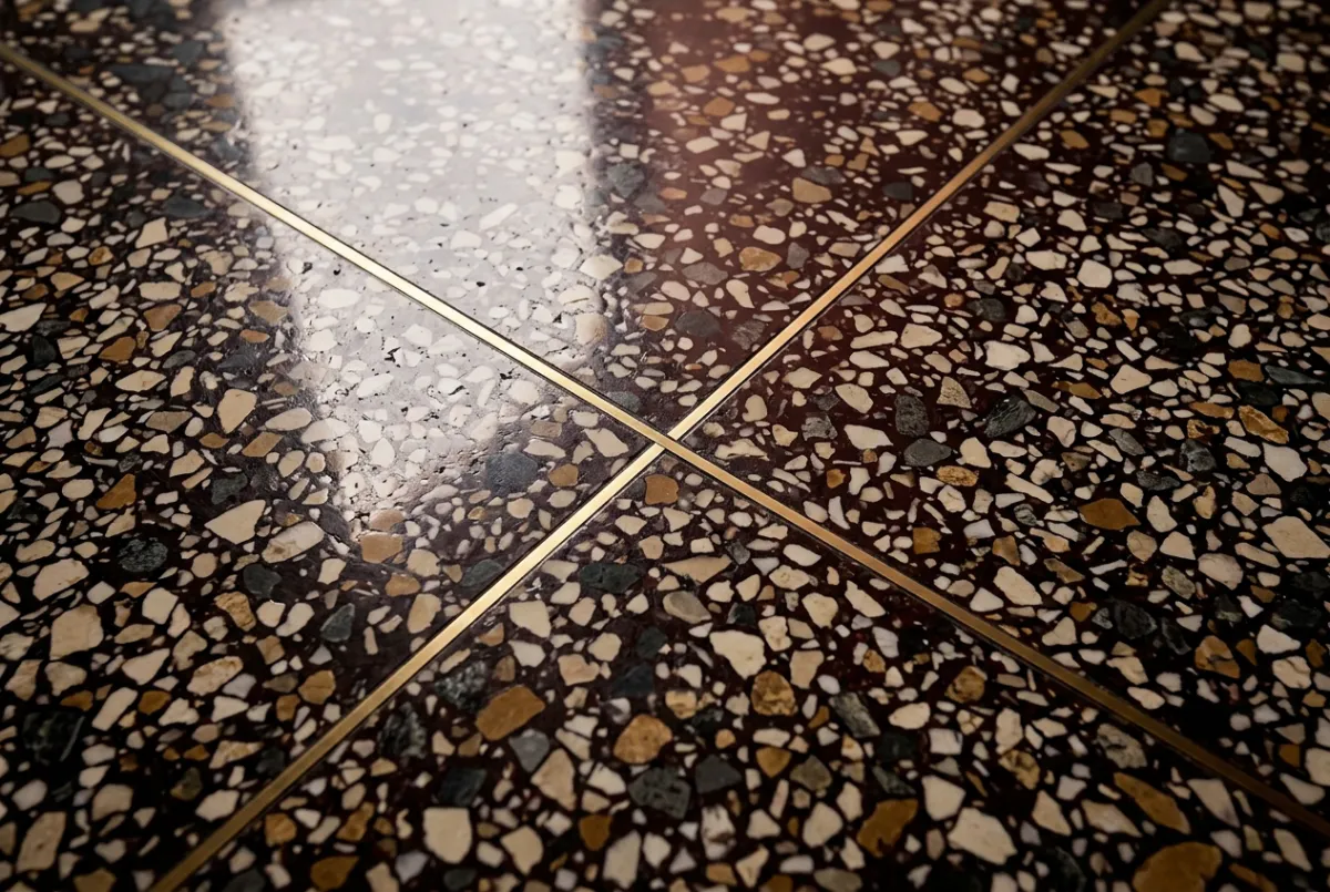 High-end polished terrazzo floor surface showing marble aggregate chips and brass divider strips