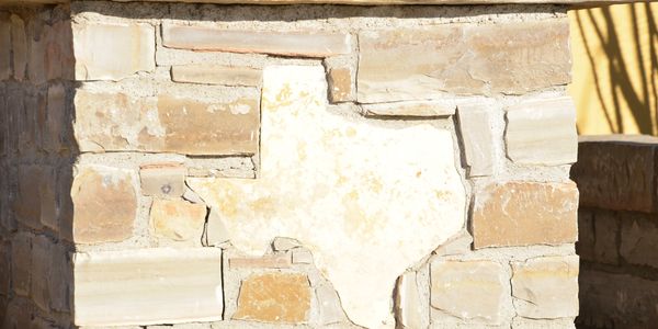 Stone wall with Texas-shaped cutout filled with lighter stone.