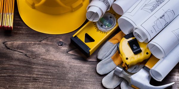 Construction tools and blueprints arranged on a wooden surface.