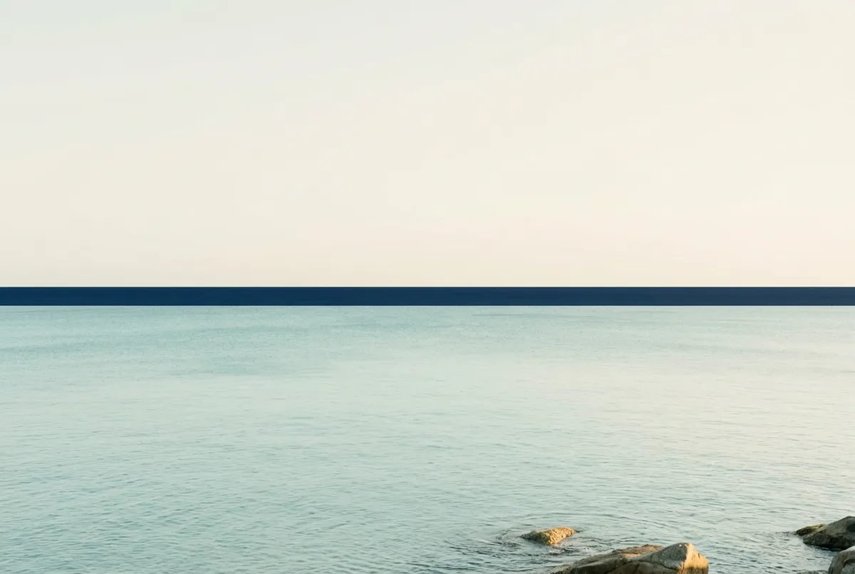 Weathered sea stones resting in calm coastal tide symbolizing self-trust and protective boundary restoration