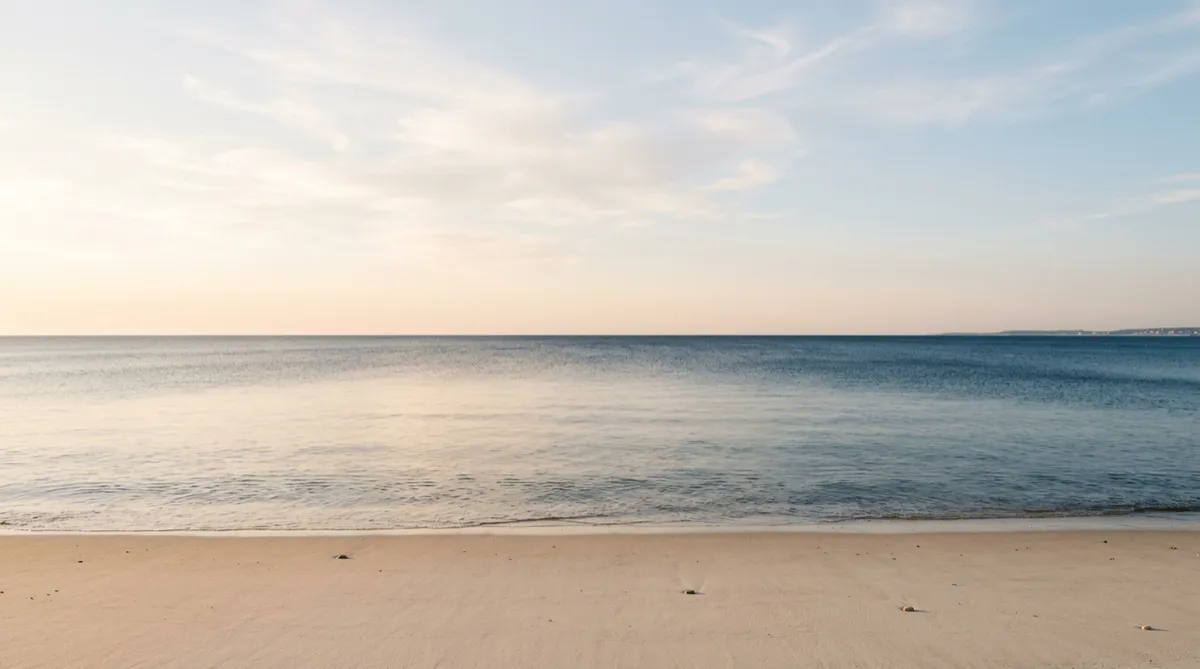 Open coastal horizon with gentle sunlight reflecting softly on the still sea surface