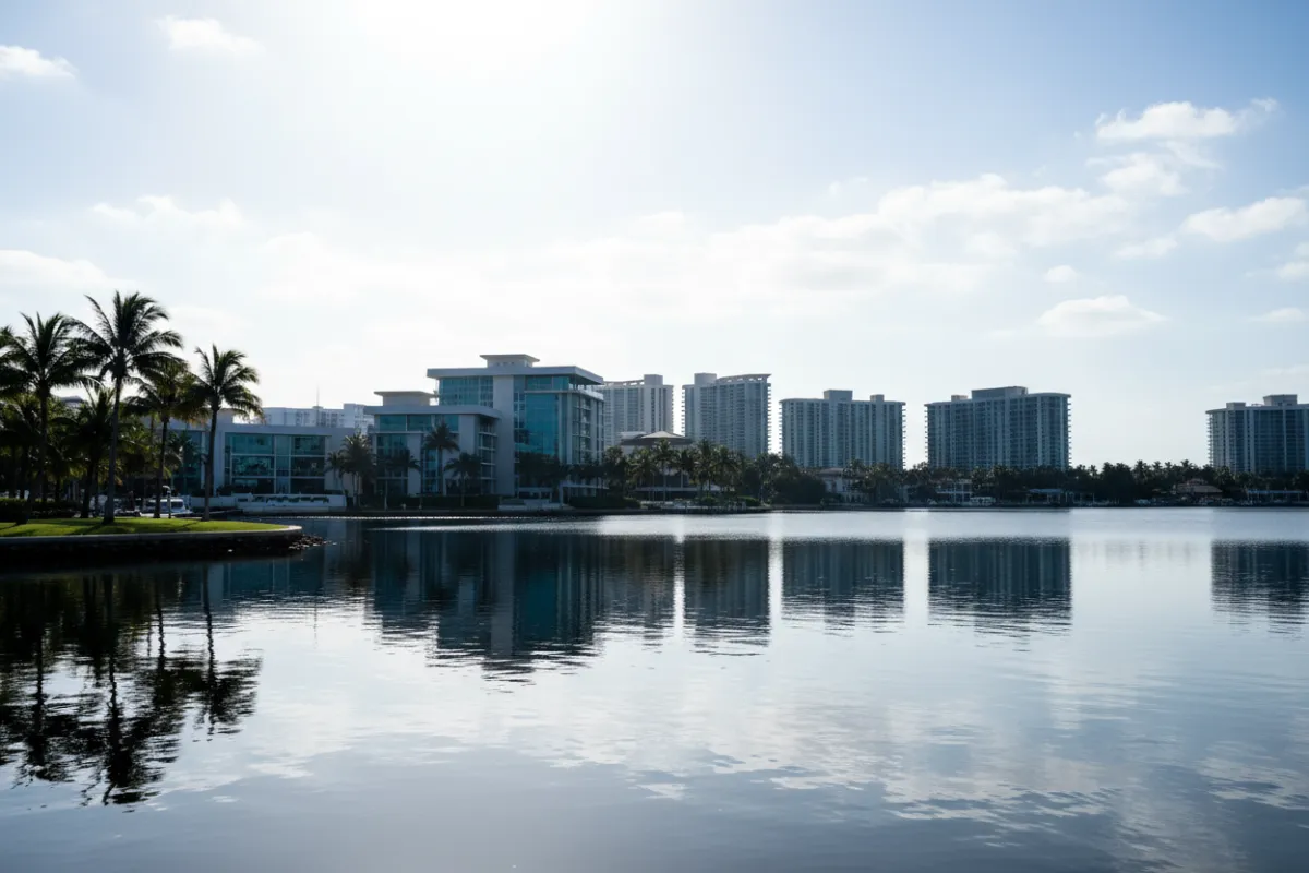 Panoramic landscape photograph of the property skyline across the intracoastal at midday, emphasizing horizon, palm silhouettes and reflective water.