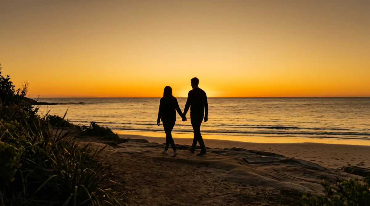 Two people holding hands silhouetted against a golden sunset