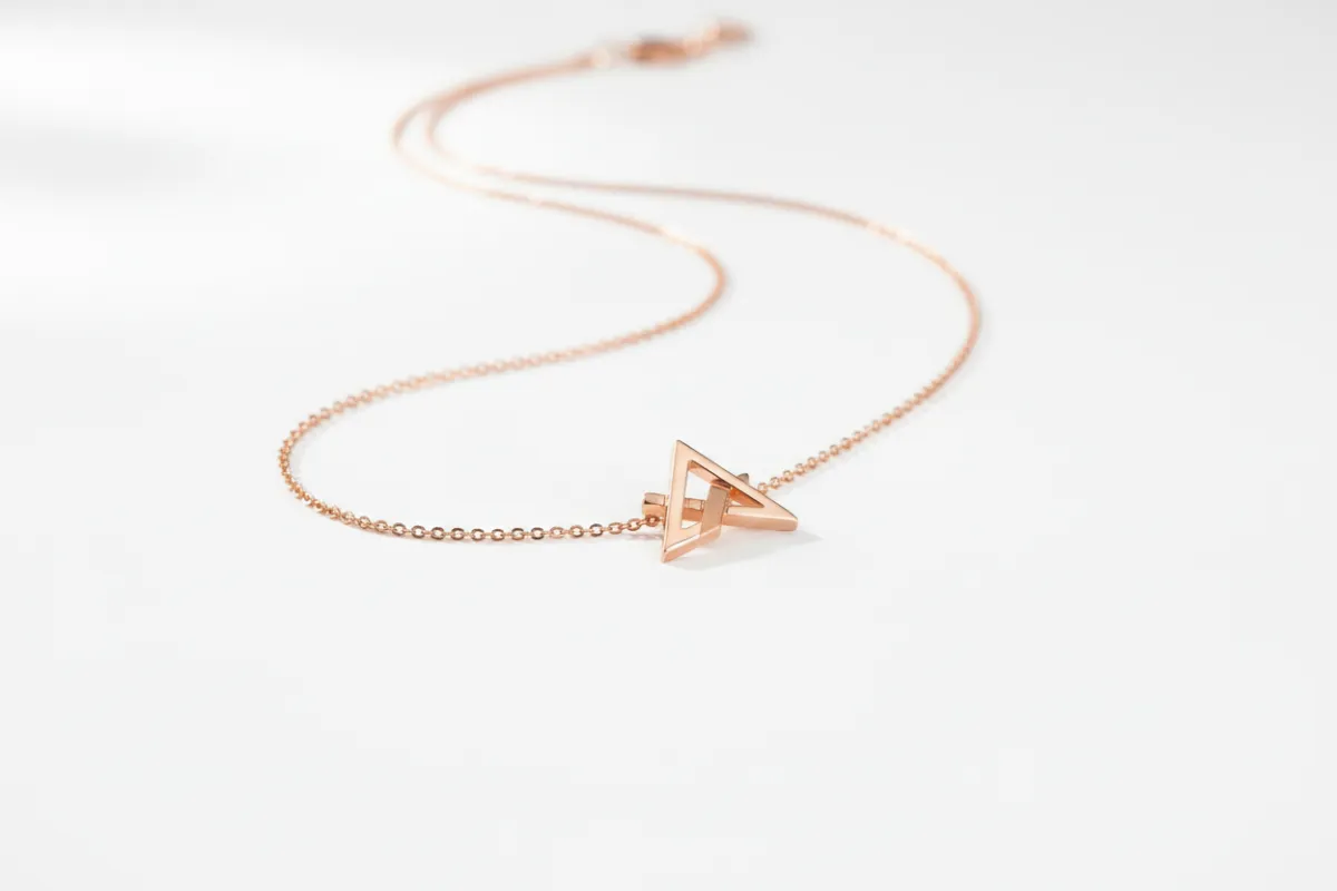 Collar minimalista de oro rosa sobre fondo blanco, enfoque en el brillo y los detalles, sin modelo, composición limpia y elegante