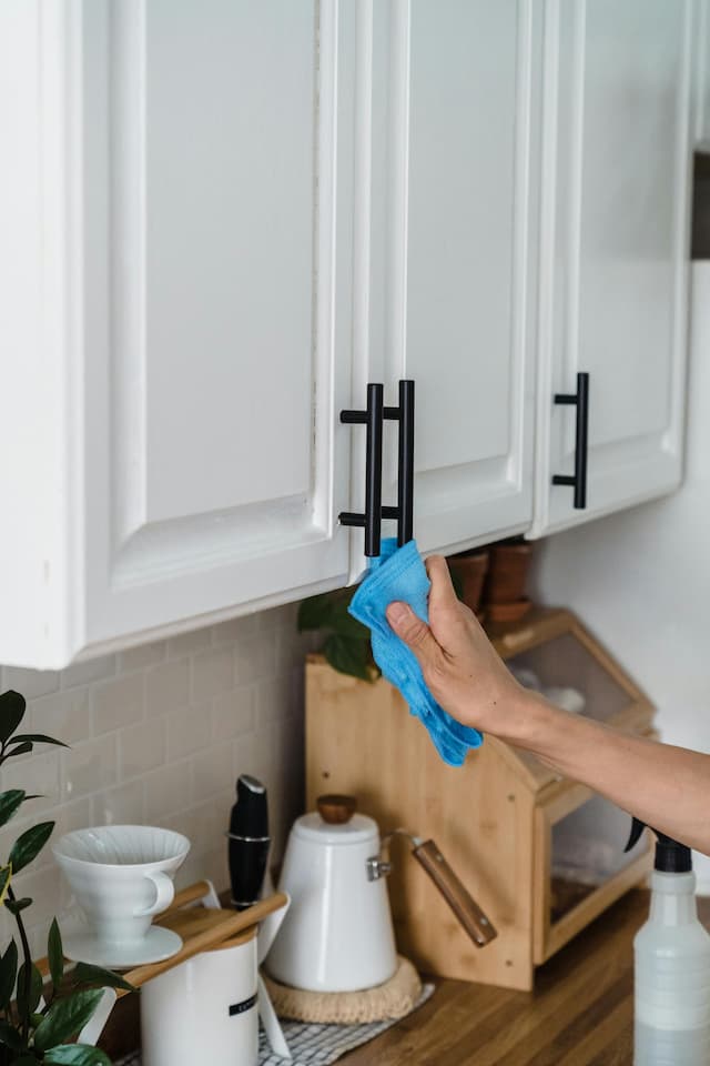 Woman cleaning kitchen cabinets