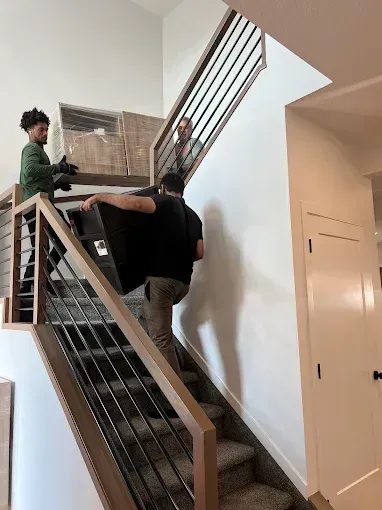 Movers carrying a dresser up stairs