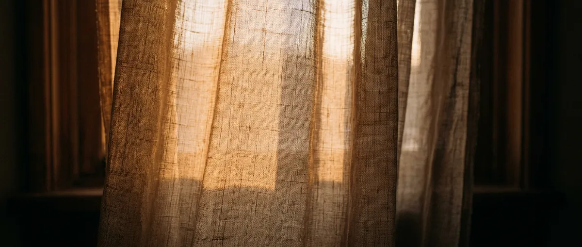 Soft warm morning sunlight filtering through delicate sheer linen curtains in a quiet, peaceful room
