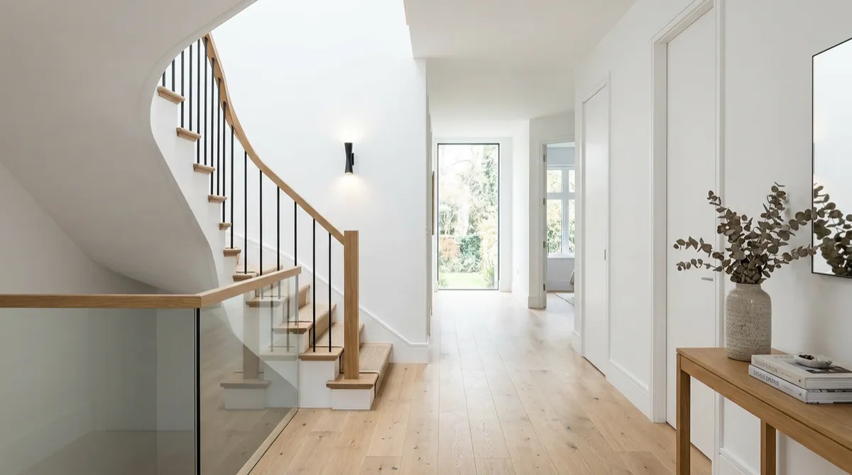 White interior hallway with wooden floor and staircase