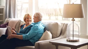 Old Couple Smiling on Couch in New Home