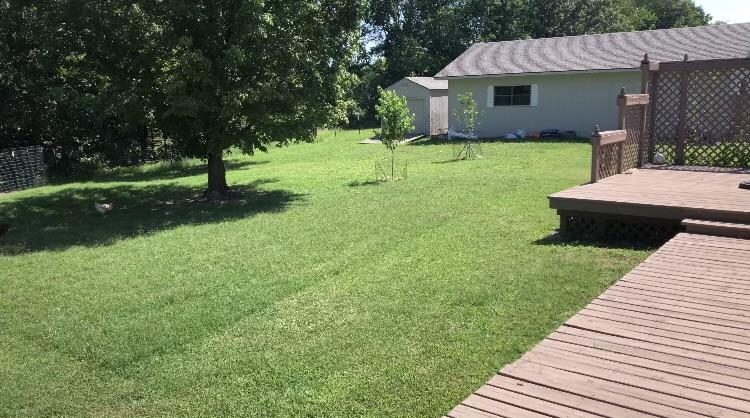 Back deck overlooking private fenced backyard with gardens