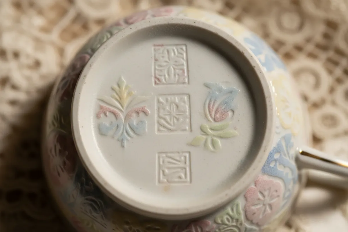 Detail of porcelain stamping and maker’s marks on a teacup, softly lit for collector appeal.