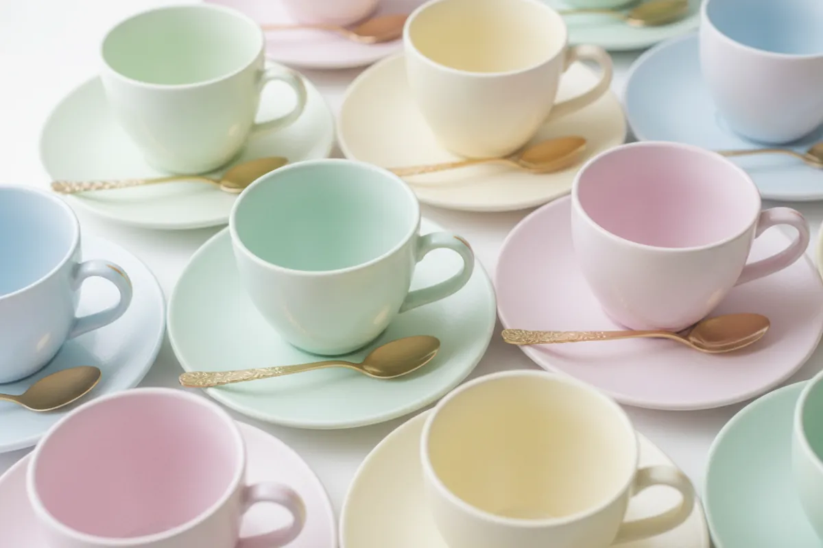 Stacked teacups with painted edges and golden spoons arranged diagonally for mosaic interest and texture.