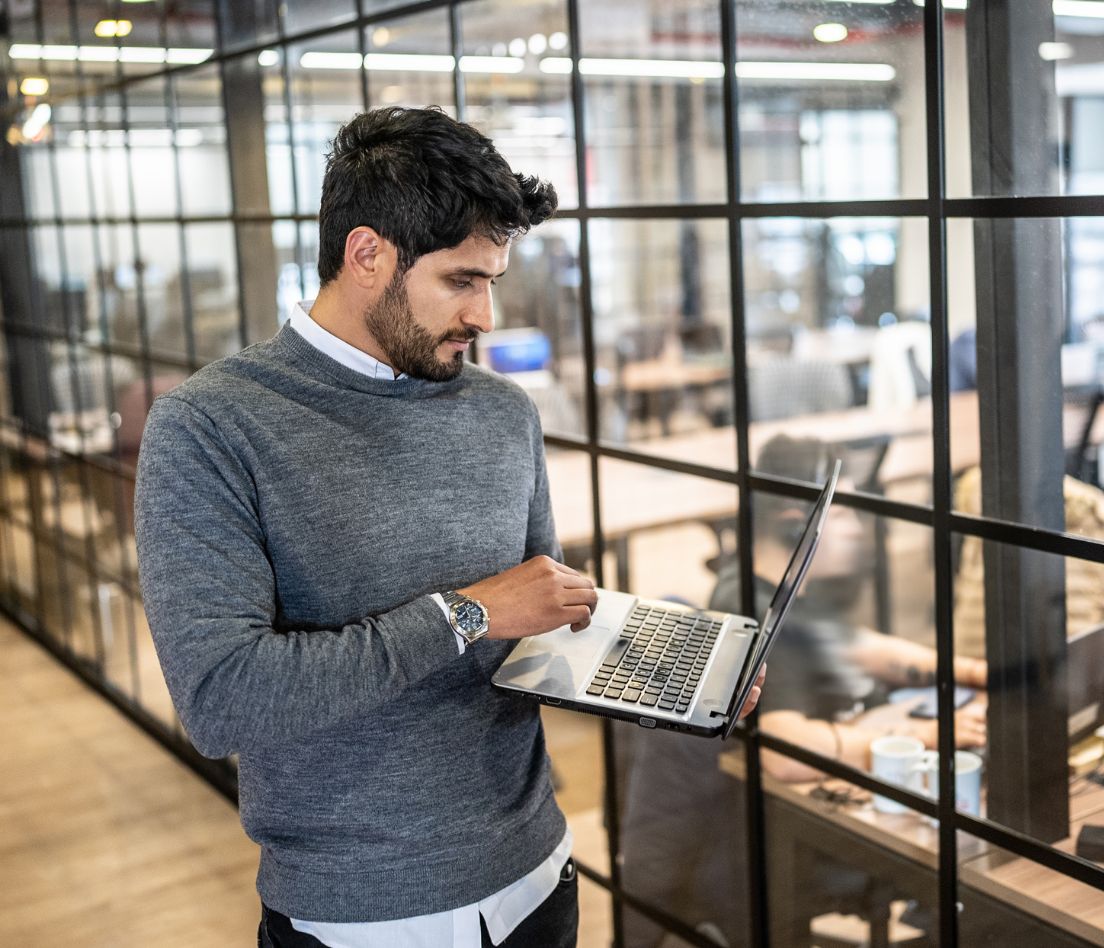 Man standing and working on a laptop