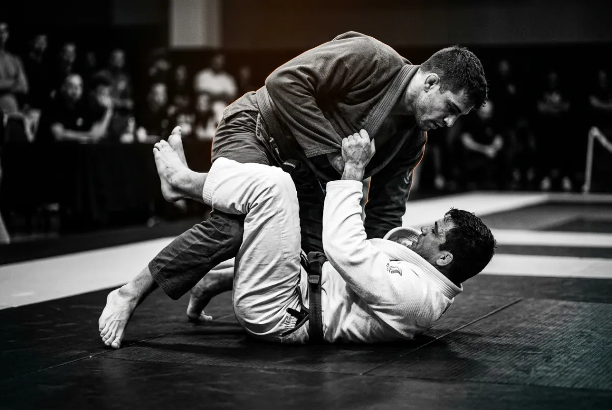 High-contrast technical guard pass execution during structured Jiu-Jitsu training