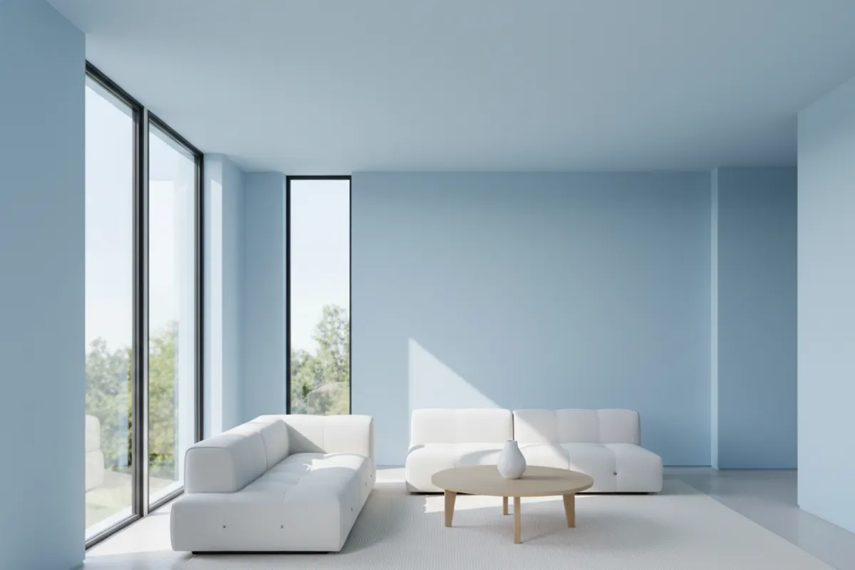 A modern living room with freshly painted light blue walls, natural sunlight streaming through large windows, and minimalistic furniture, highlighting the crisp lines and smooth finish of the paintwork.
