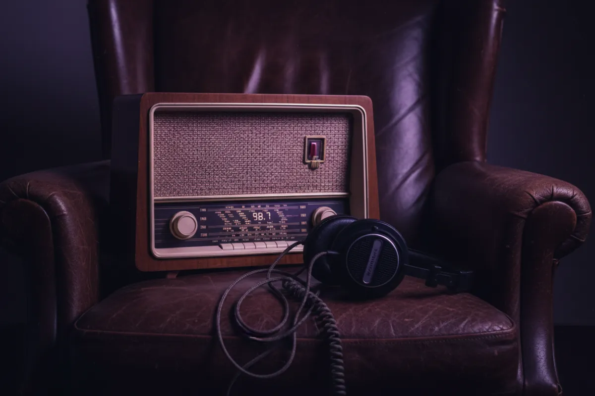 Vintage FM radio and studio headphones in moody purple lighting.