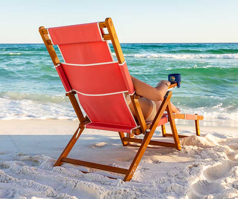 Woman relaxing on a wooden beach chair with DockaDrink attached