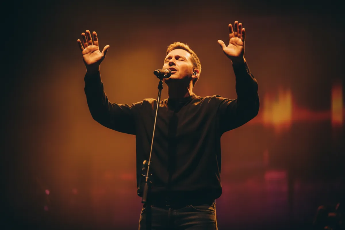 Worship leader with raised hands on stage
