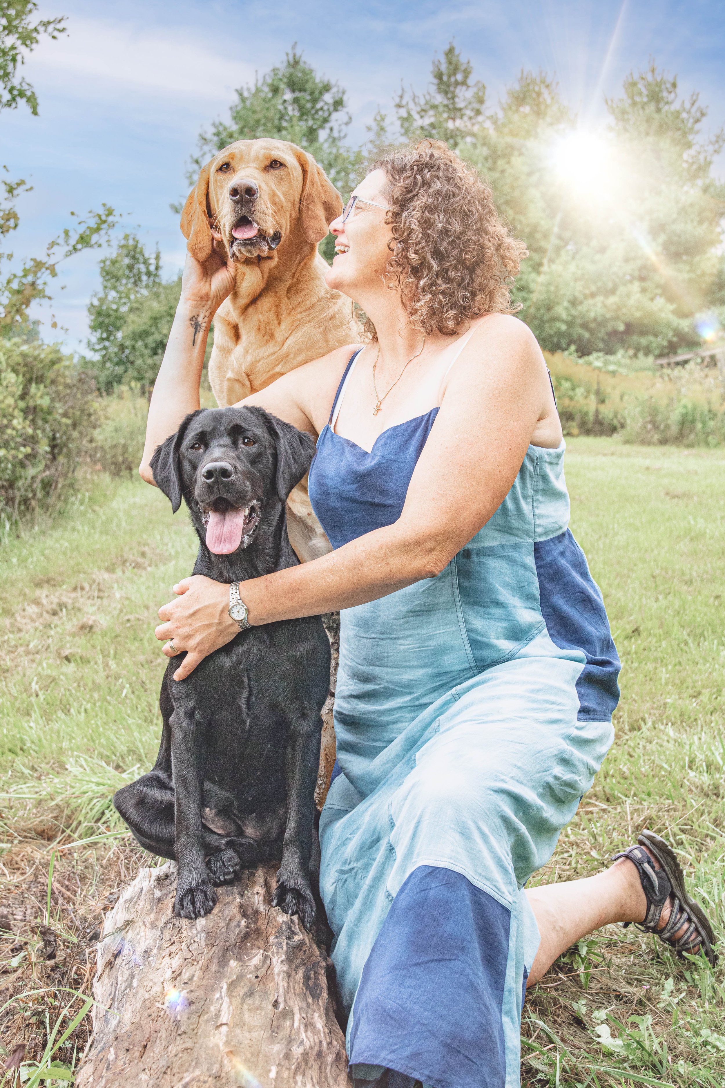 Woman hugging golden retriever and black lab