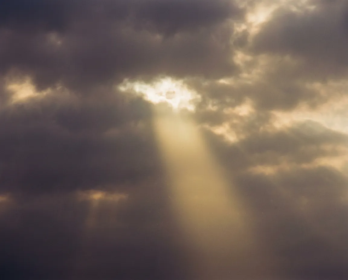 A warm ray of golden sunlight breaking through morning clouds, symbolizing spiritual hope and redemption