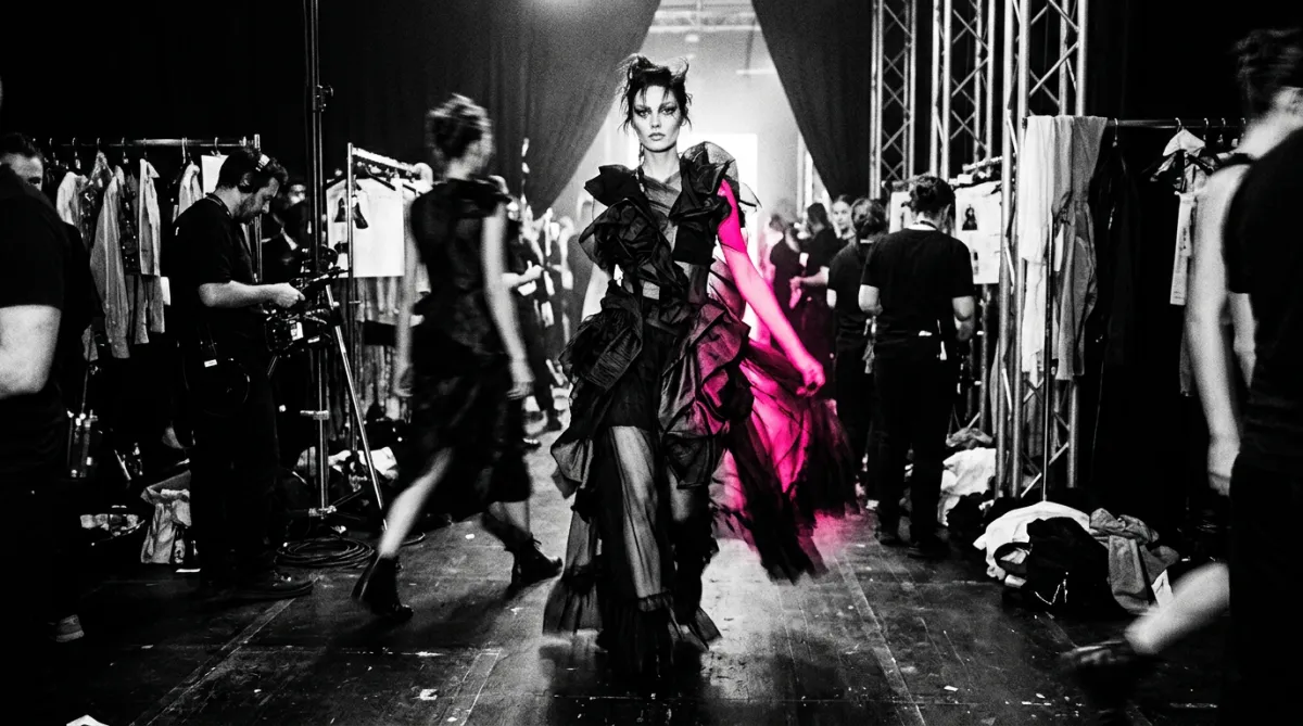 High-contrast cinematic black and white flash photography blur in a high-fashion backstage runway atmosphere