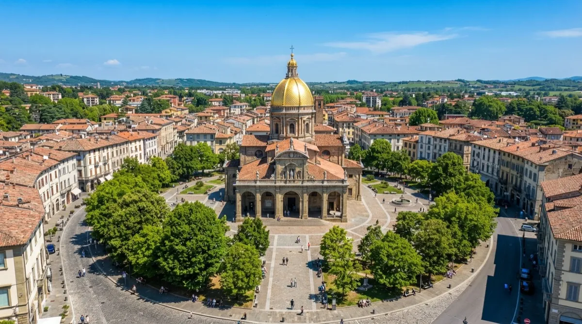 Aerial view of a town square with a historic building featuring a golden dome, surrounded by trees and a clear blue sky.