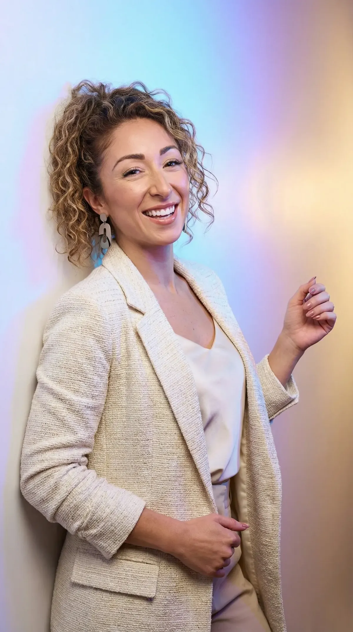 Smiling woman in a light blazer and earrings, standing against a softly lit background, representing Zenith Marketing Solutions and its focus on tailored marketing strategies for medical practices.