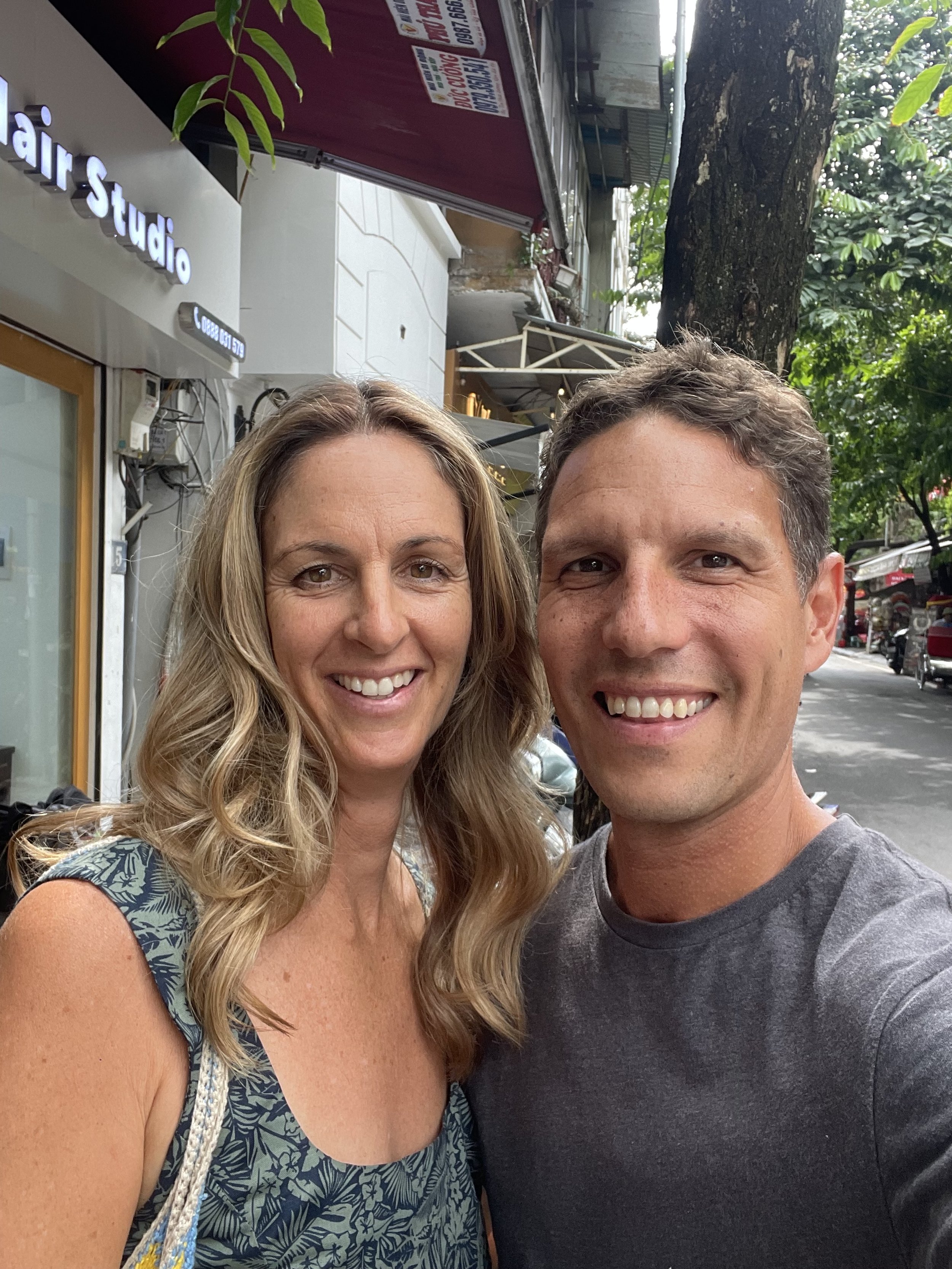 A smiling woman and a man taking a selfie outdoors