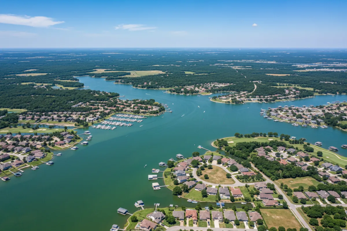 Aerial view of Lake Conroe and Montgomery County, Texas, with neighborhoods, marinas, and green spaces, under a clear sky. The image highlights the area’s natural beauty and vibrant communities.
