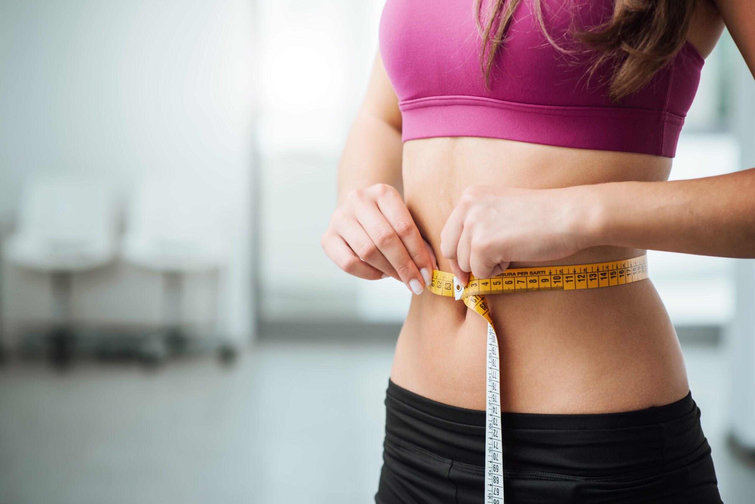 Woman measuring waist illustrating weight loss progress and Semaglutide therapy results.