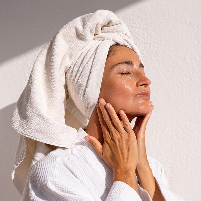 Woman touching face with towel on head