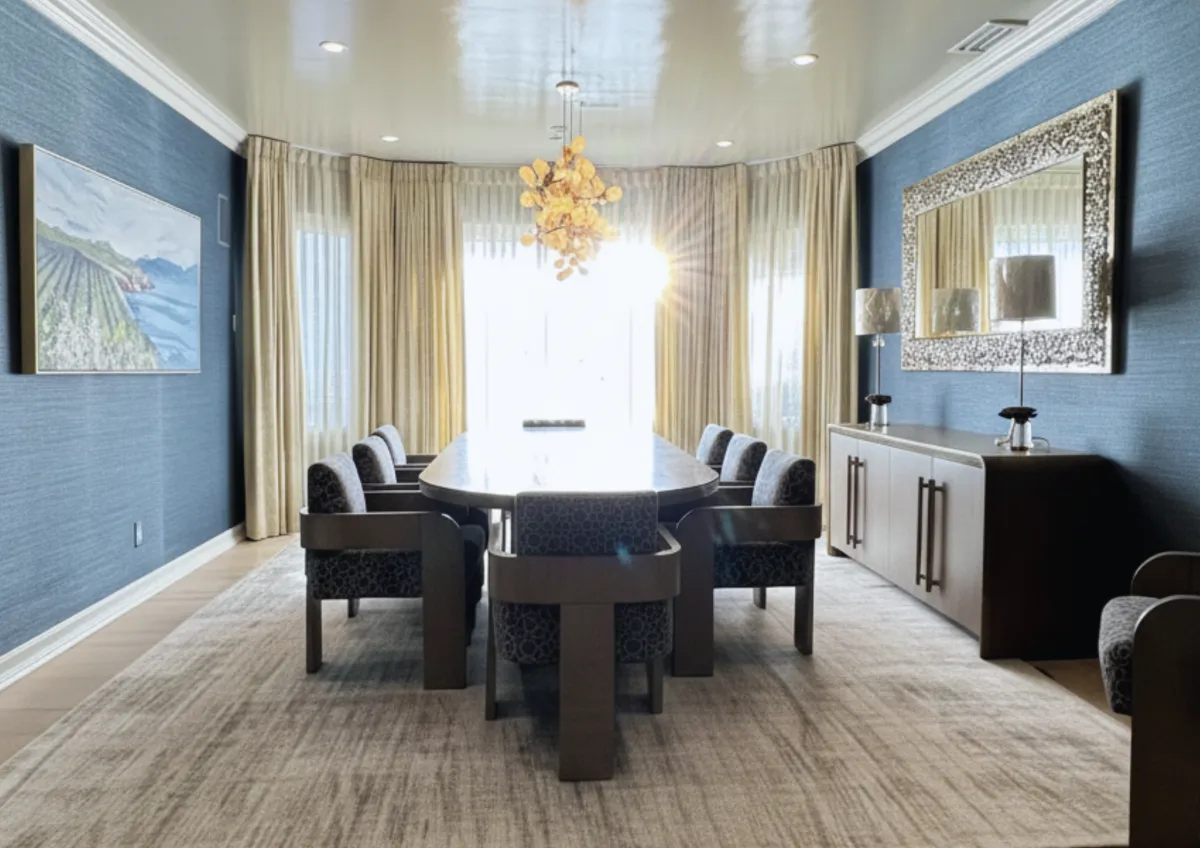Cool-toned dining room with layered sheer drapery and woven wood shades adding warmth through texture, not color