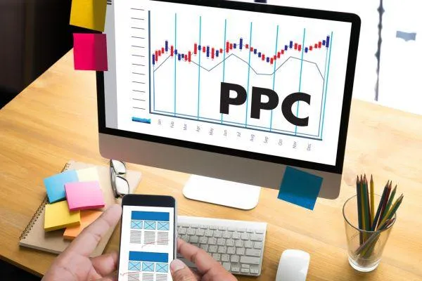 PPC advertising analytics on computer screen with growth chart, smartphone wireframe design, and digital marketing workspace.