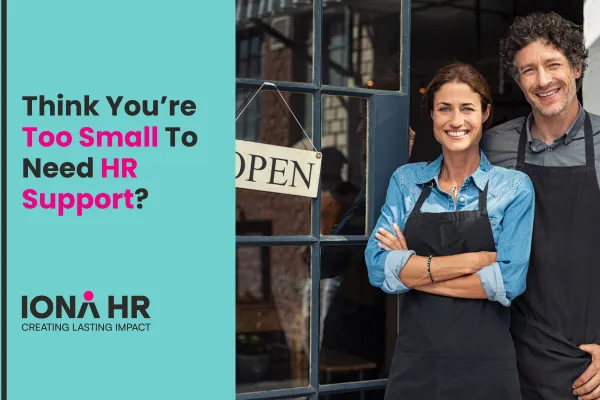 Two smiling small business owners in aprons standing at the entrance of their shop with an "Open" sign in the window. Text on the left reads: "Think You're Too Small To Need HR Support?" with the IONA HR logo and tagline "Creating Lasting Impact" underneath.