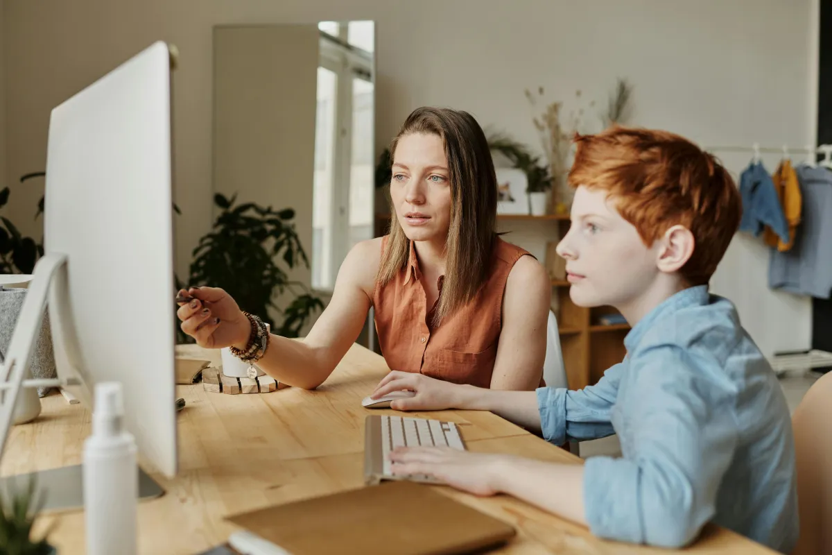 A mom helping her son with her homework on the computer