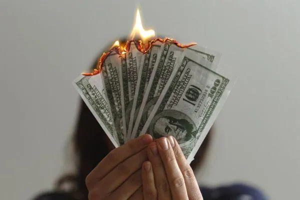 woman holding 100 dollar bill that are burning