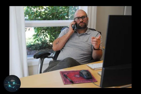 A business professional on the phone while working at a computer, symbolizing multitasking and missed calls. This image relates to the blog's focus on how Missed Call Text Back keeps customers engaged by instantly responding when you're unavailable.