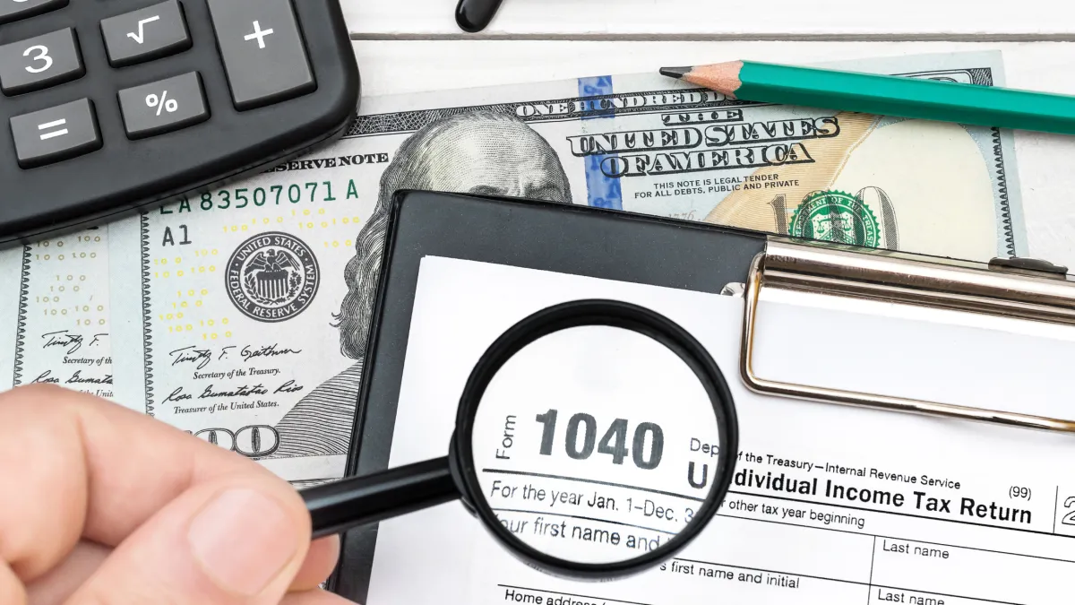 a business owner holding a magnifying glass over a tax document