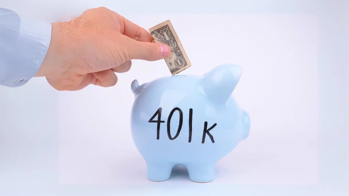 A hand places a dollar bill into a blue piggy bank labeled "401k," symbolizing retirement planning.