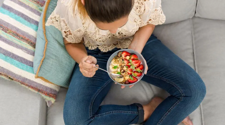 Women sitting in her ADU eating a bowl of yogurt with fruits.