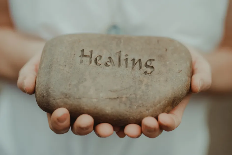 woman holding stone that reads healing