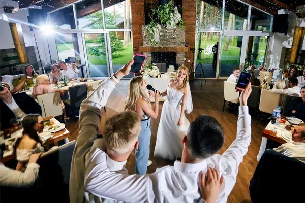 The bride, a shining star of wedding entertainment, passionately sings into the microphone at the reception as guests eagerly capture treasured photos and videos.