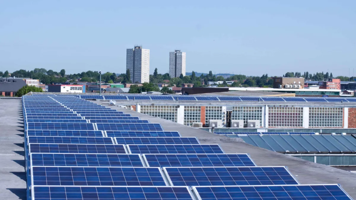 Alt text: "Large commercial solar panel installation on a flat roof in an urban setting, with multiple rows of panels requiring regular maintenance. Office buildings and residential towers are visible in the background, highlighting the scale of commercial properties that benefit from scheduled cleaning and maintenance.