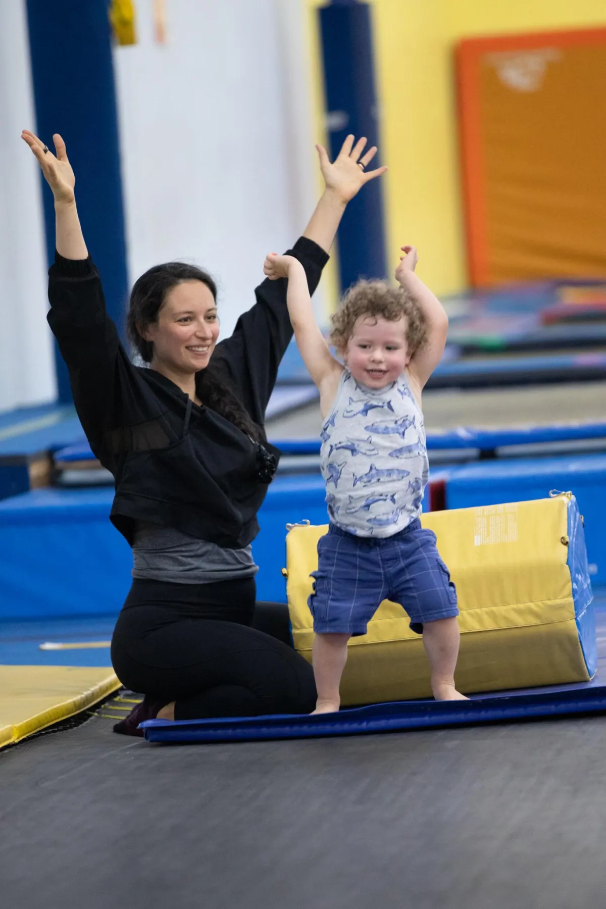 Child with autism smiling and celebrating after trampoline therapy session, coached on tumble track.