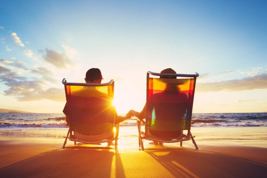 Two early retirees relaxing in chairs on beach