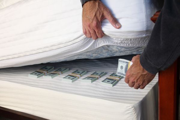 Reaching for emergency fund money safety net under mattress