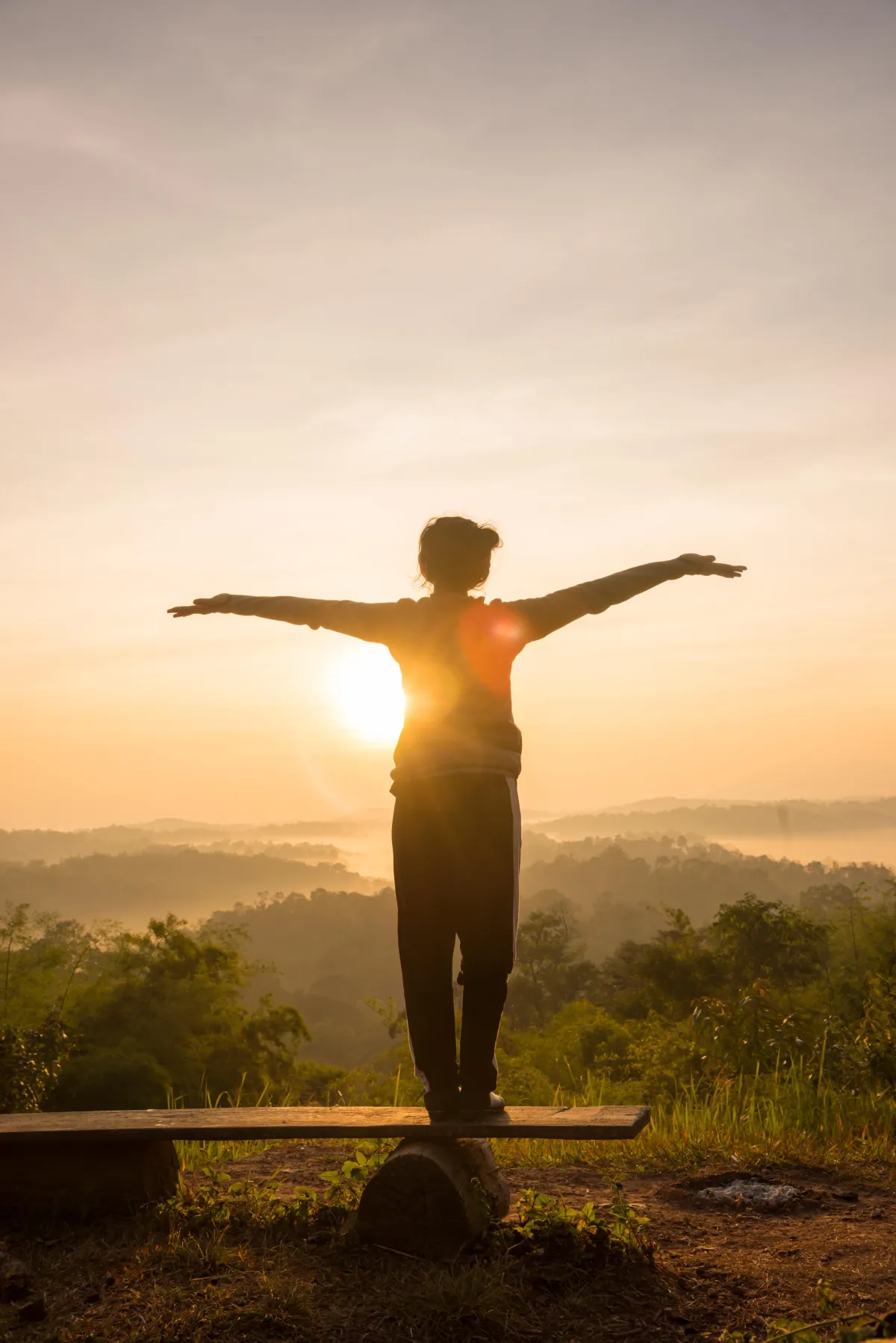 woman standing outside at sunset arms open wide